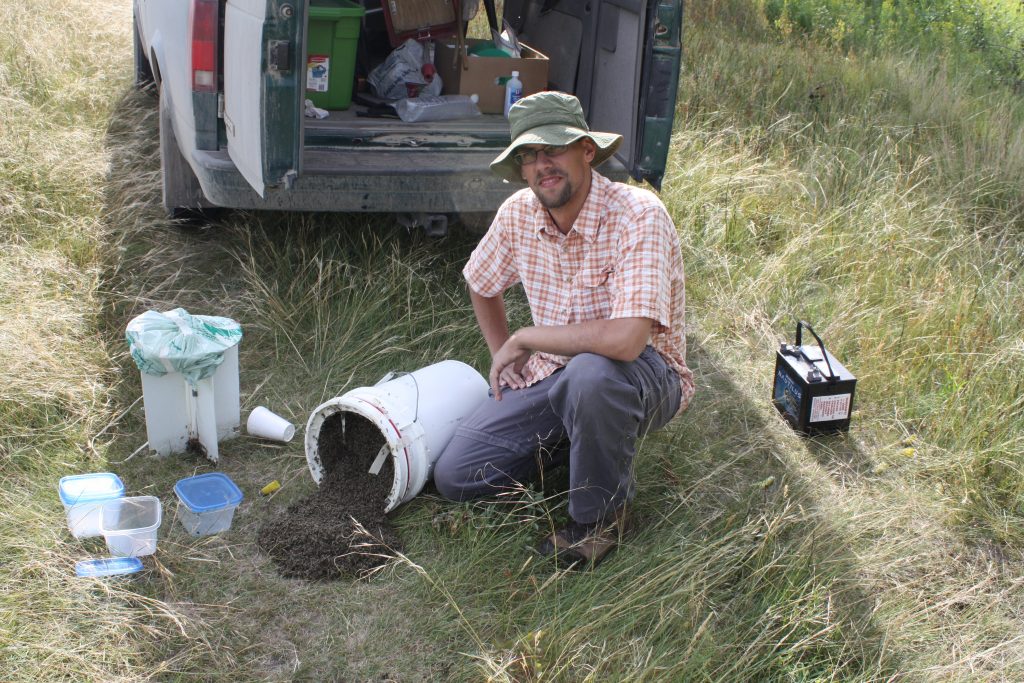 Me kneeling beside a bucket on its side with midges spilling out.